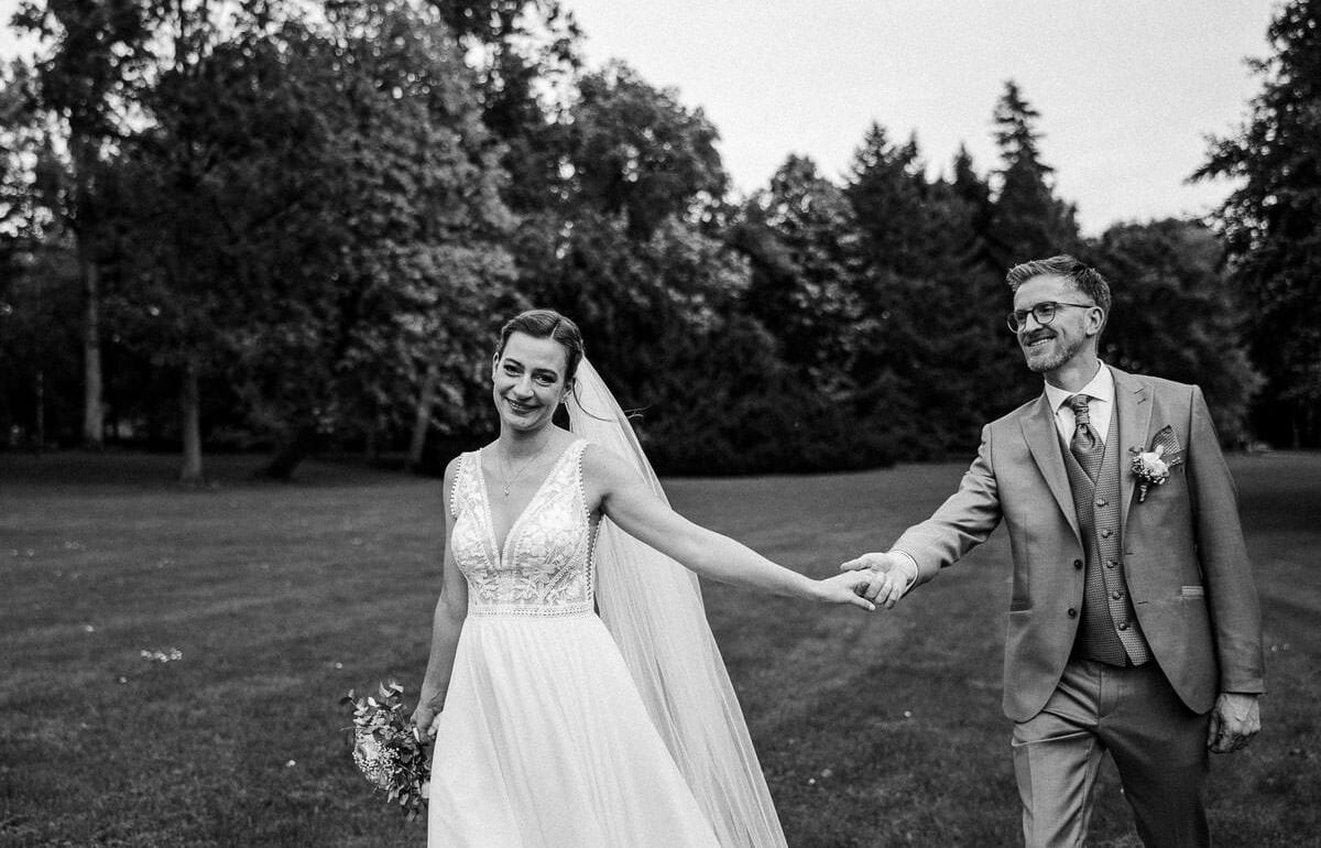 hochzeitspaar geht über die wiese vor schloss wolfsburg