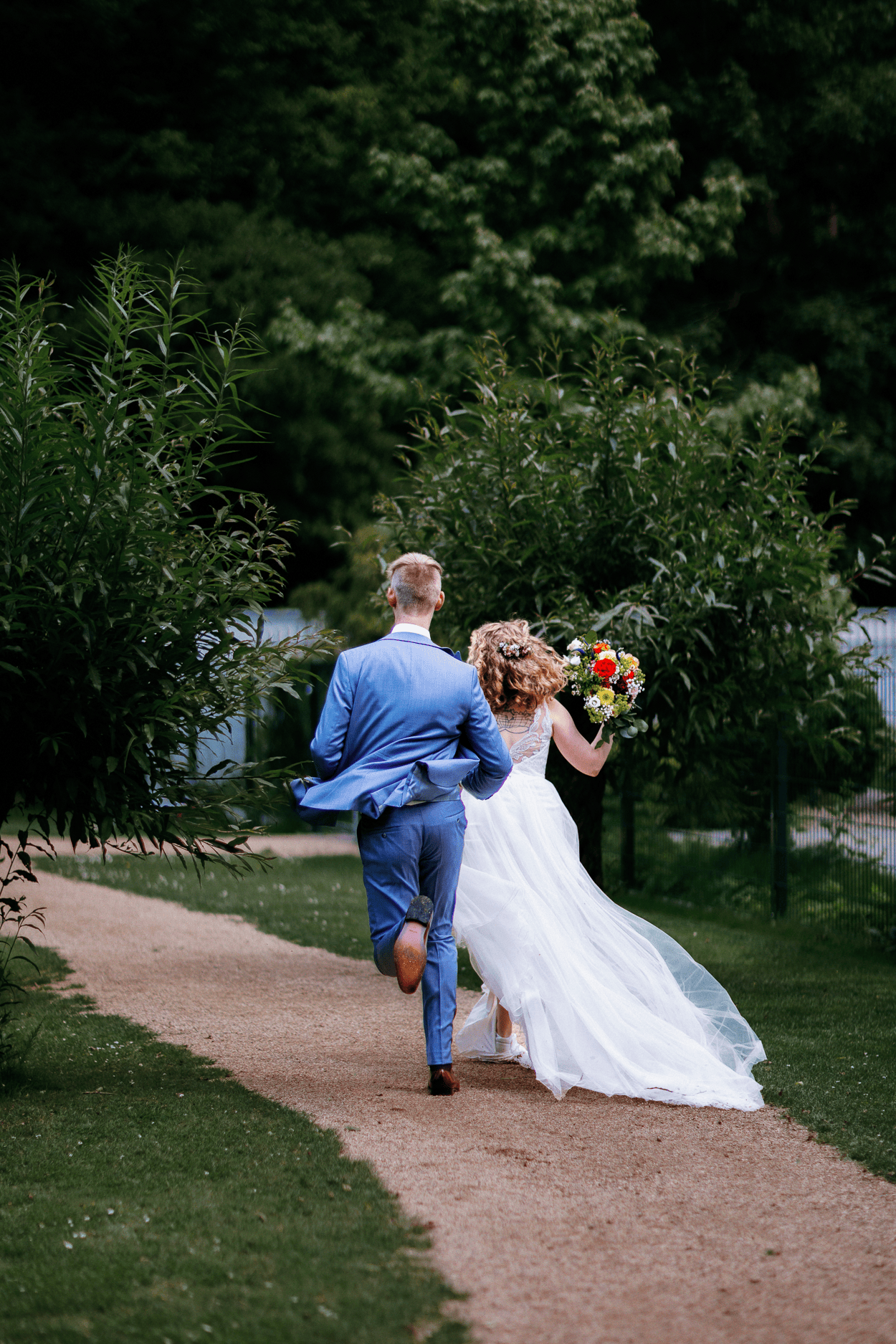 Brautpaar läuft Hand in Hand im Park des Waldhaus Ölper