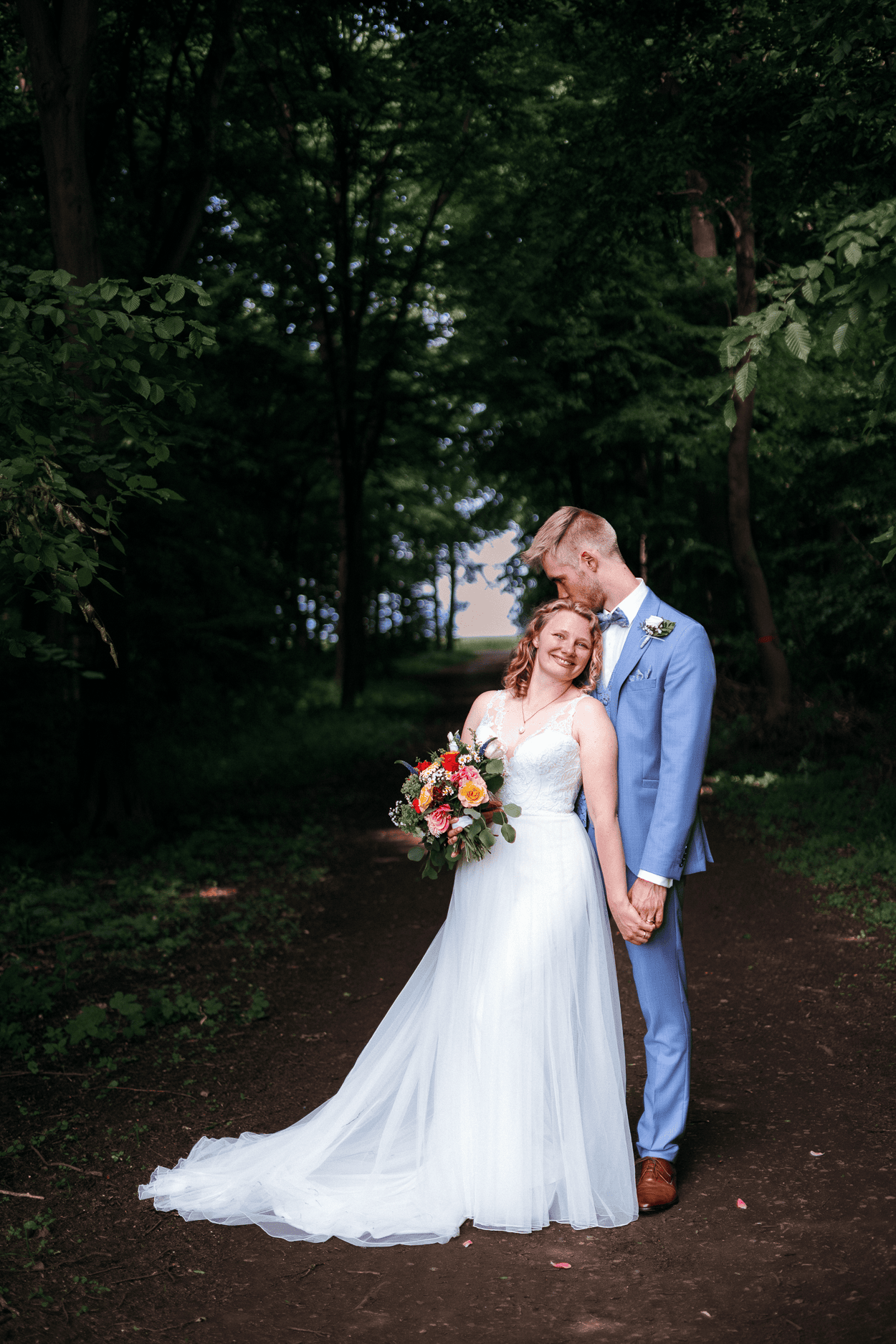 Brautpaar im Wald mit Blumenstrauß