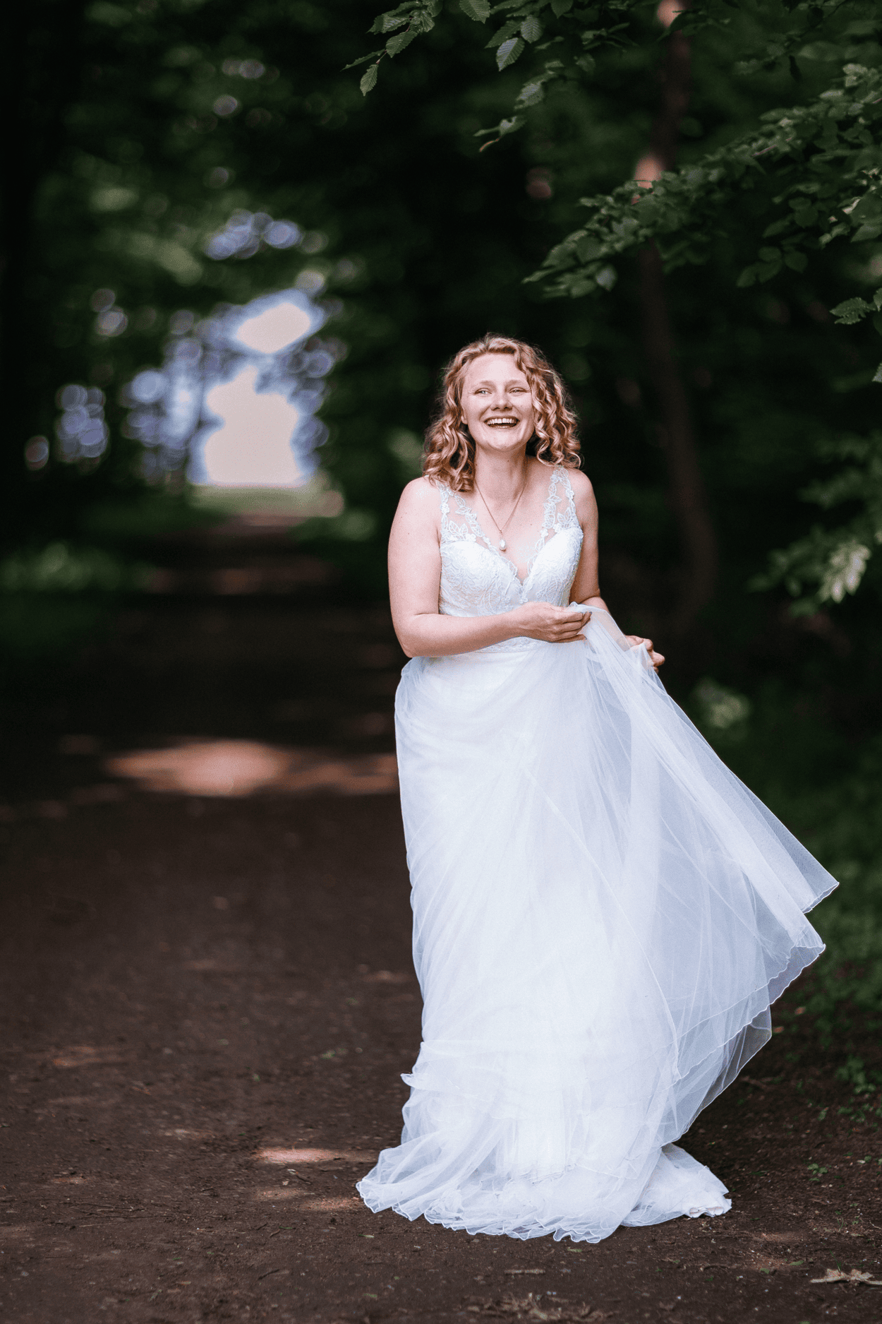 Lachende Frau im Hochzeitskleid im Wald