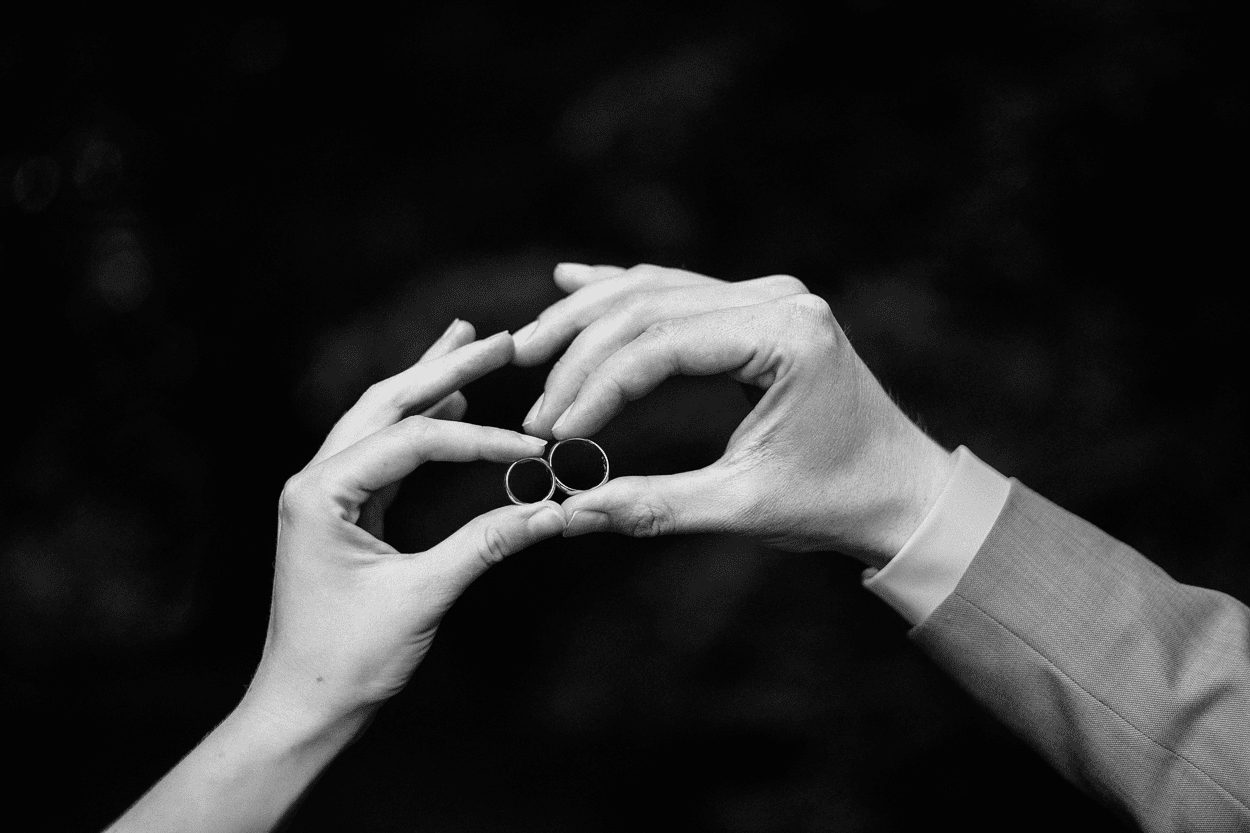 Zwei Hände halten Eheringe in Schwarzweiß