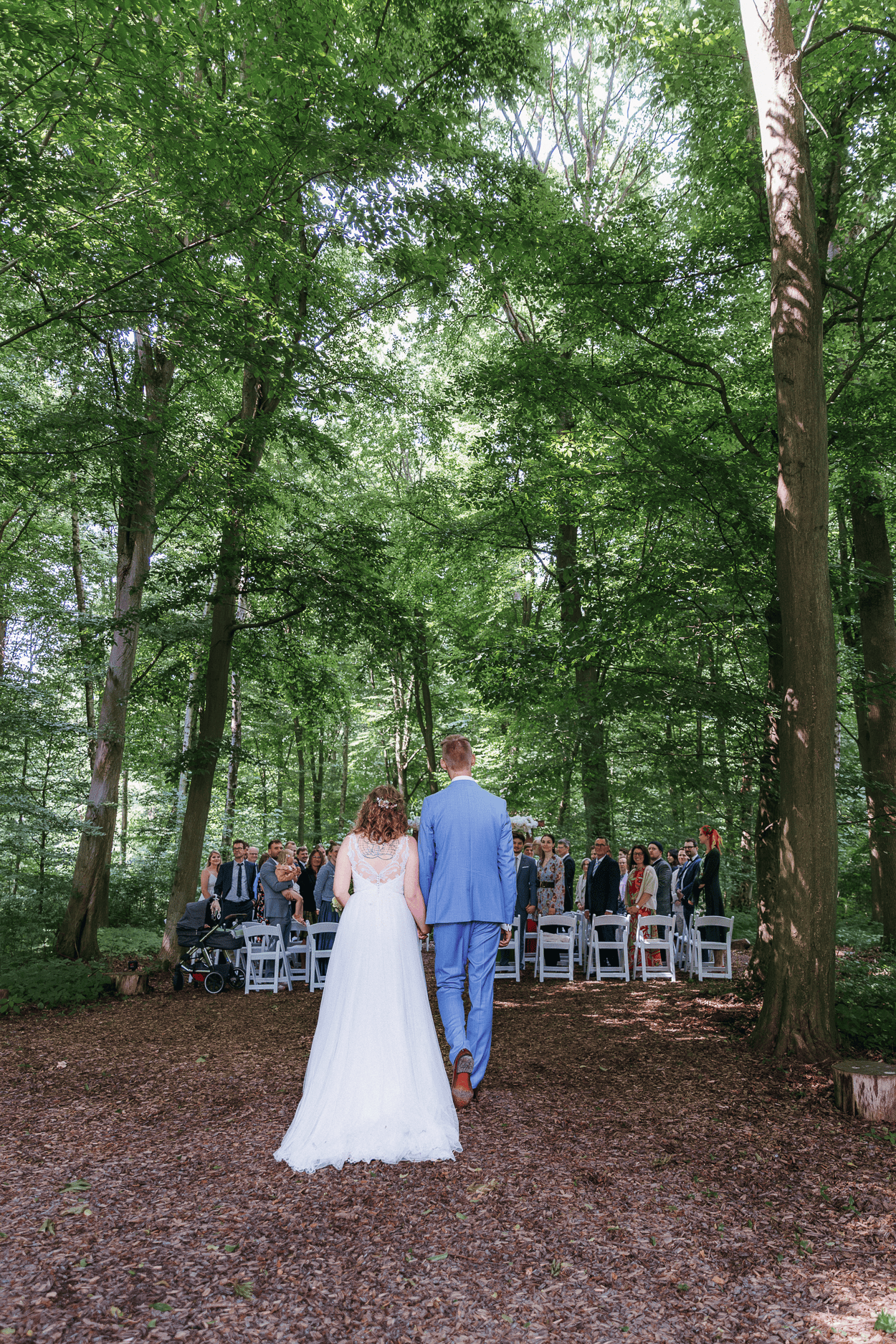 Hochzeitspaar im Wald, Gäste warten sitzend.