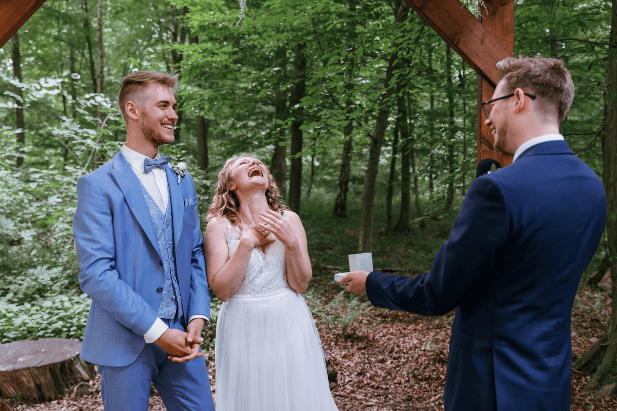 Lachendes Brautpaar bei der Trauung im Wald