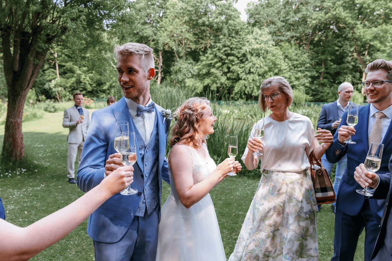 Hochzeitsgäste beim Anstoßen im Freien.