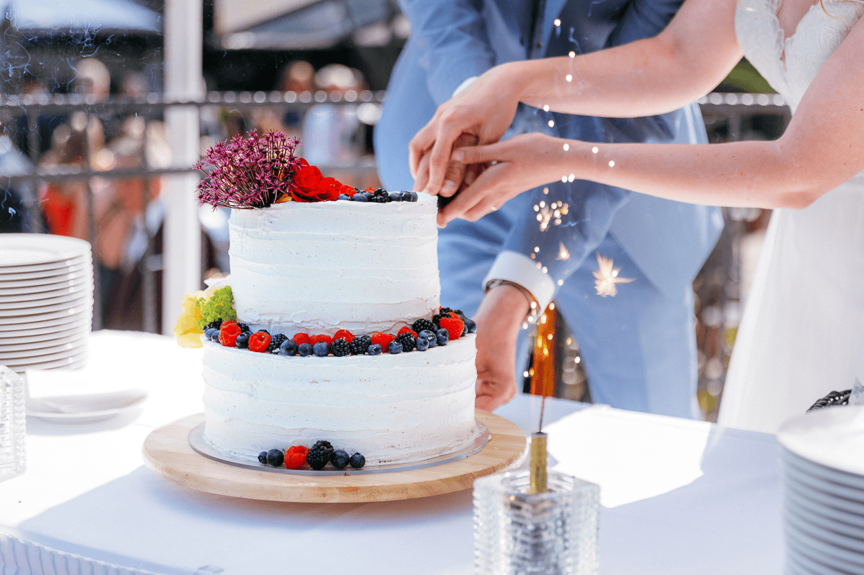 Hochzeitstorte mit Beeren, Paar schneidet an