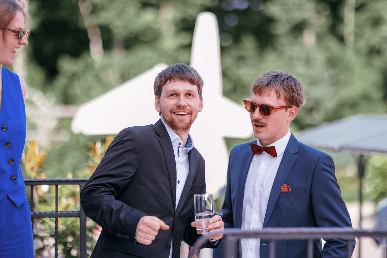 Drei Personen im Anzug unterhalten sich draußen.