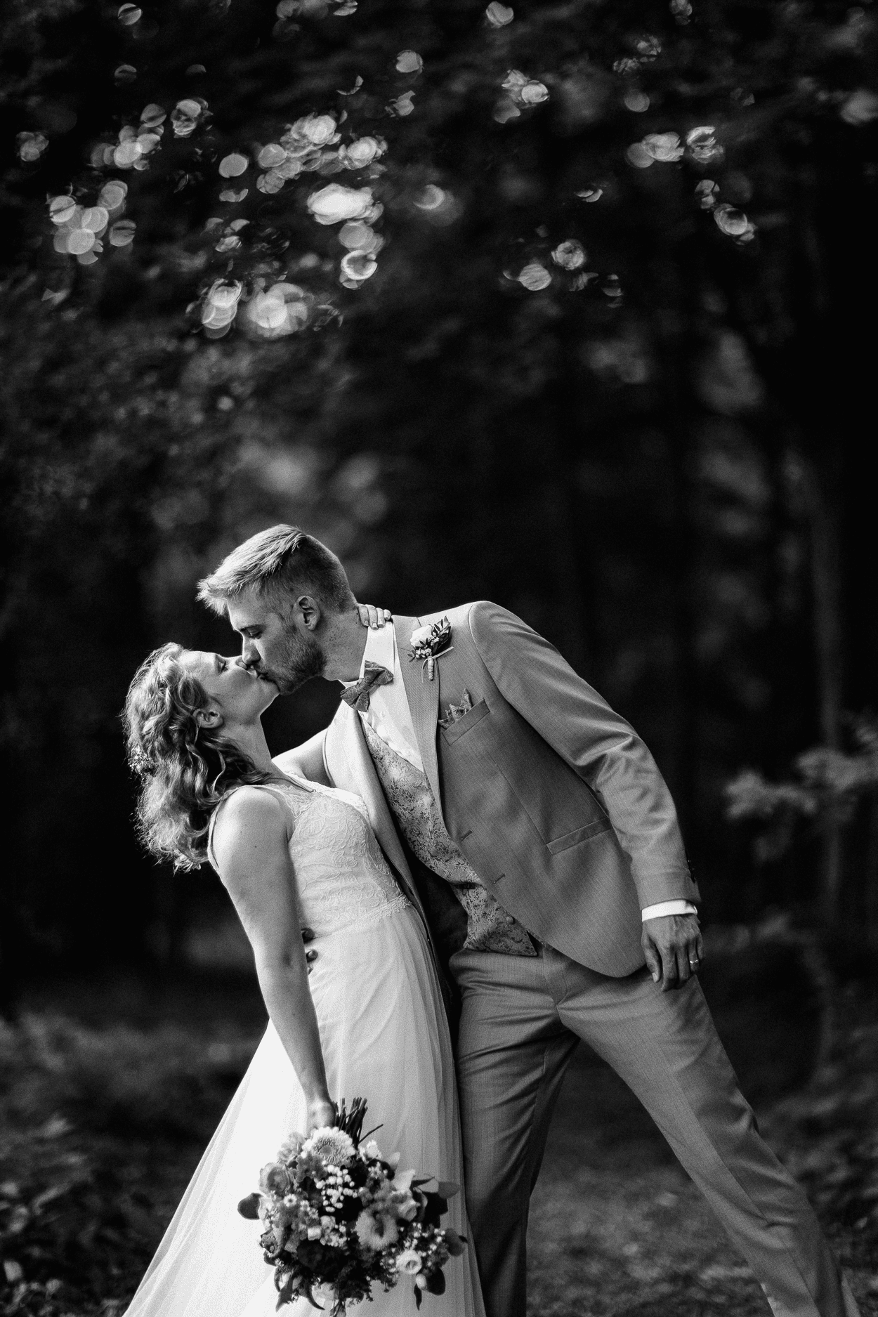 Brautpaar küsst sich im Wald, schwarz-weiß.