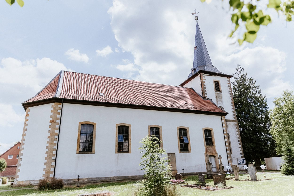 Außenansicht der Dorfkirche mit rotem Ziegeldach und Turm als Location der Trauung