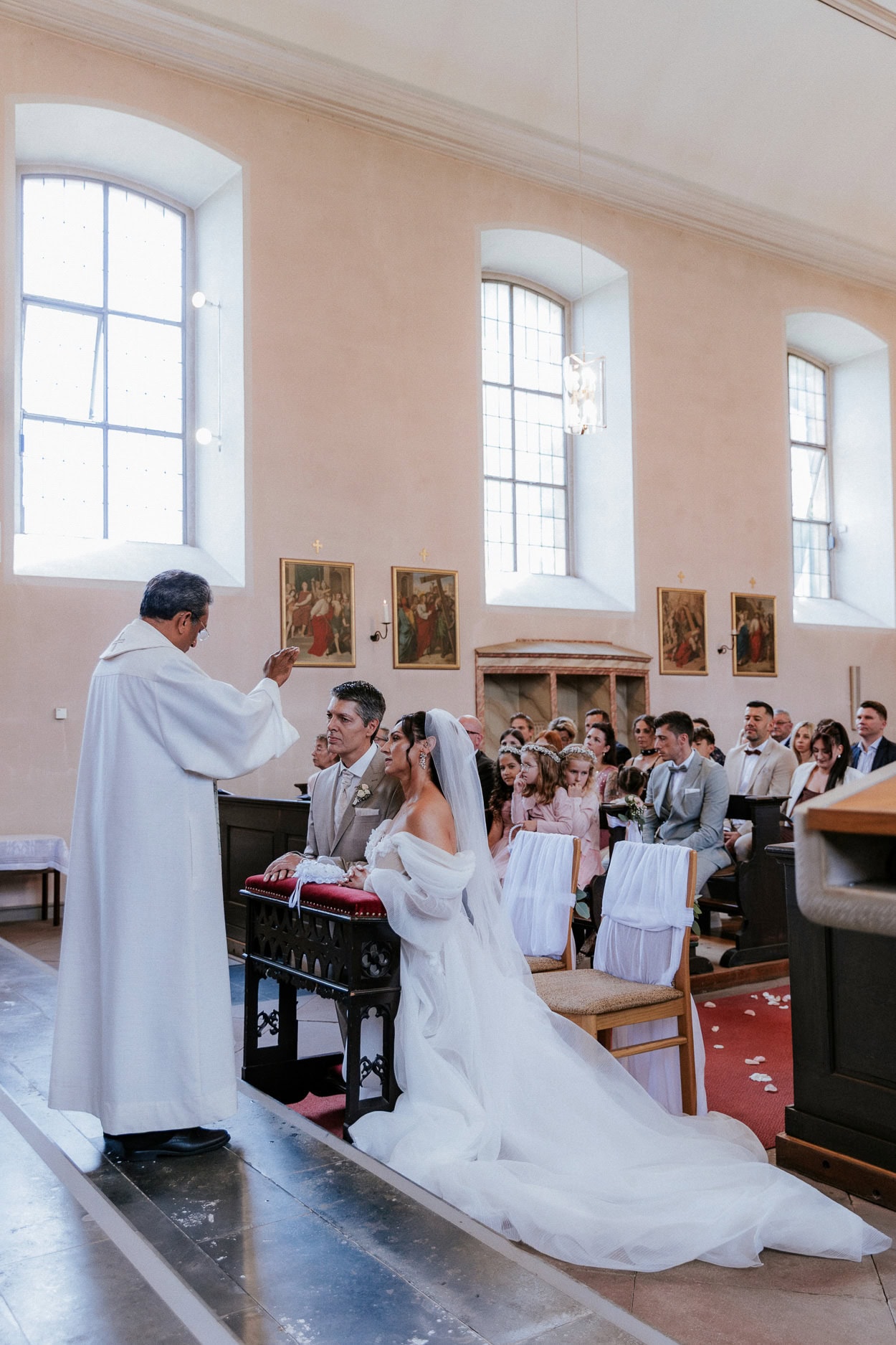 Priester segnet das knieende Brautpaar am Altar der Kirche