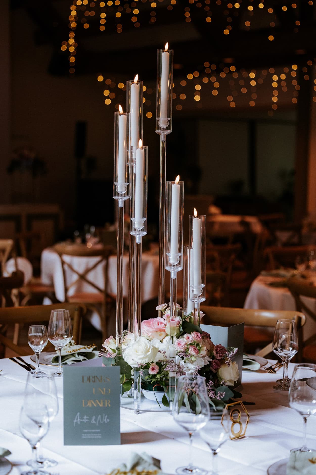 Festlich gedeckter Hochzeitstisch mit hohen Kerzenständern und rosa-weißem Blumengesteck