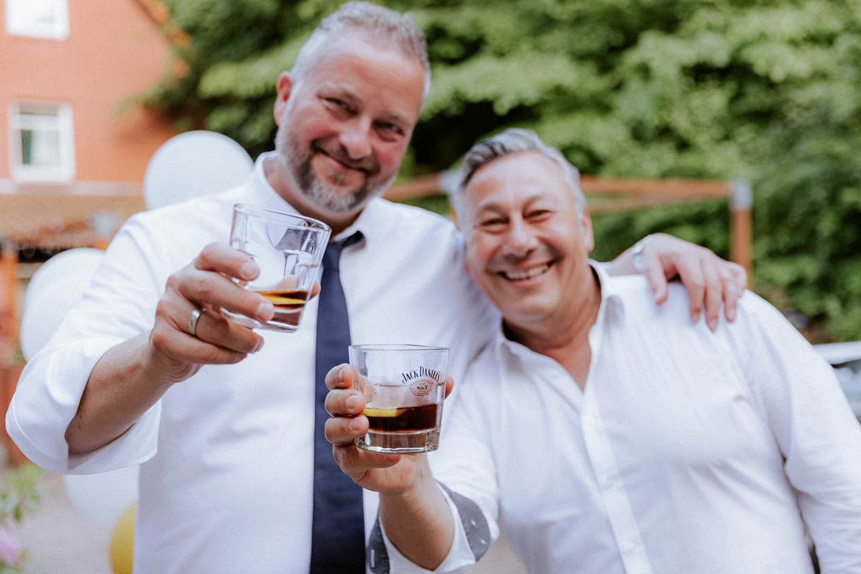 Zwei Männer stoßen lächelnd mit Whiskygläsern an