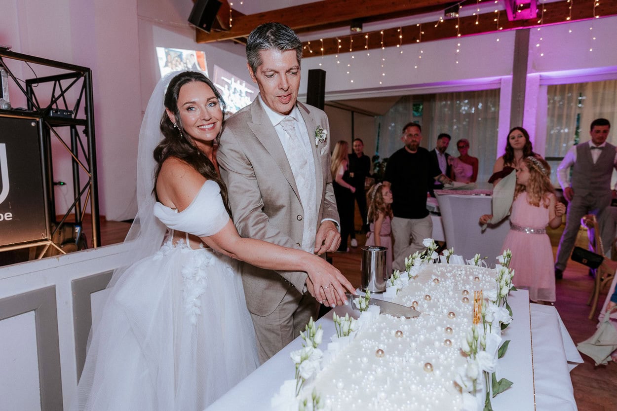 Braut und Bräutigam schneiden gemeinsam die Hochzeitstorte an